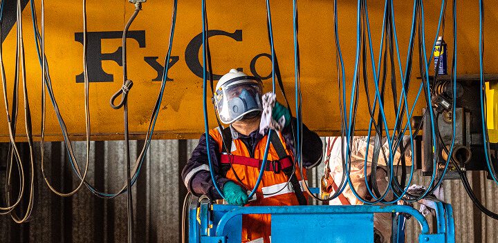 Técnico realizando mantenimiento preventivo sobre el puente de una grúa