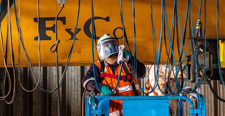Técnico realizando mantenimiento preventivo sobre el puente de una grúa