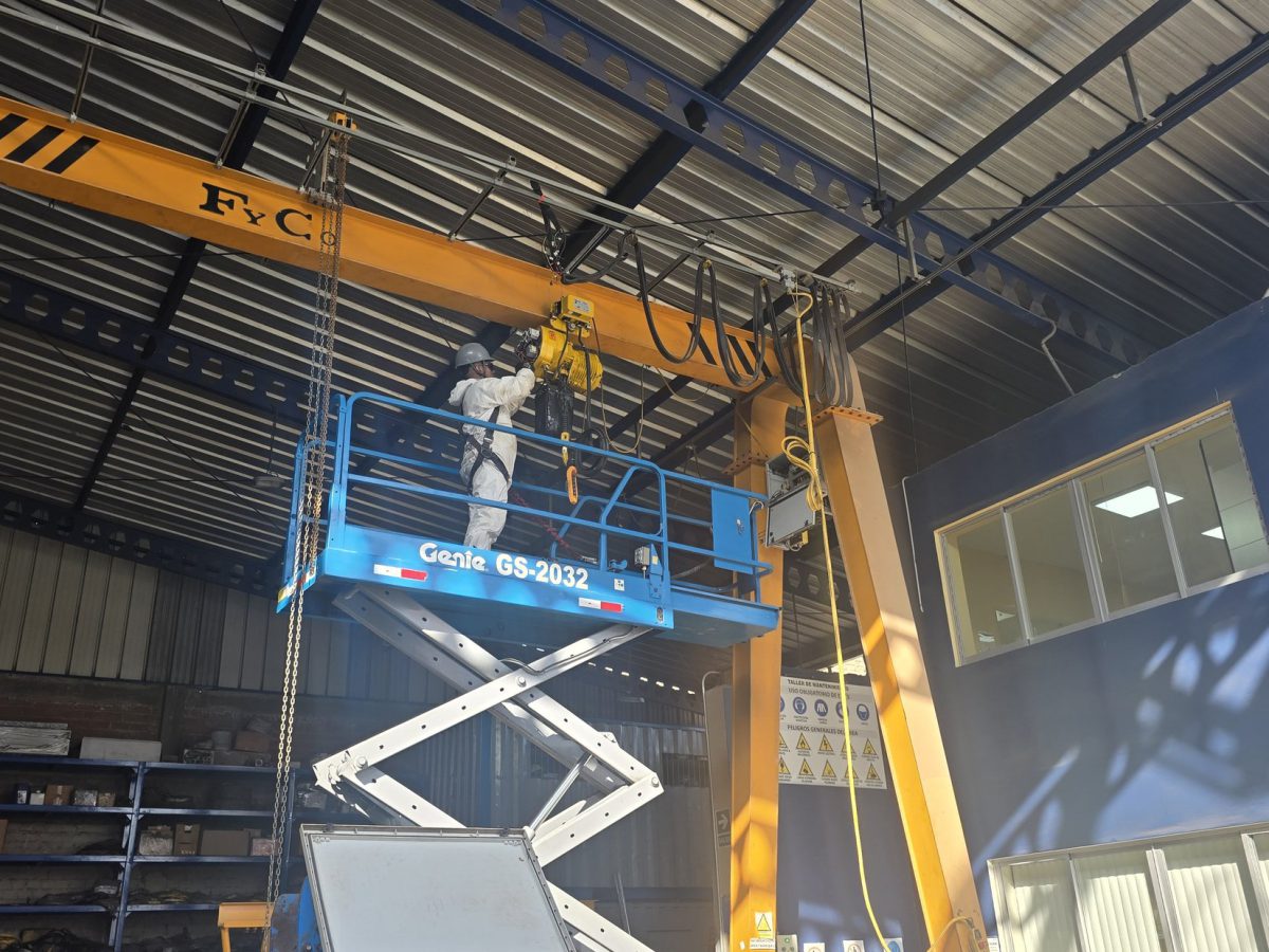 Técnico realizando mantenimiento a un polipasto de grúa puente desde una plataforma elevadora