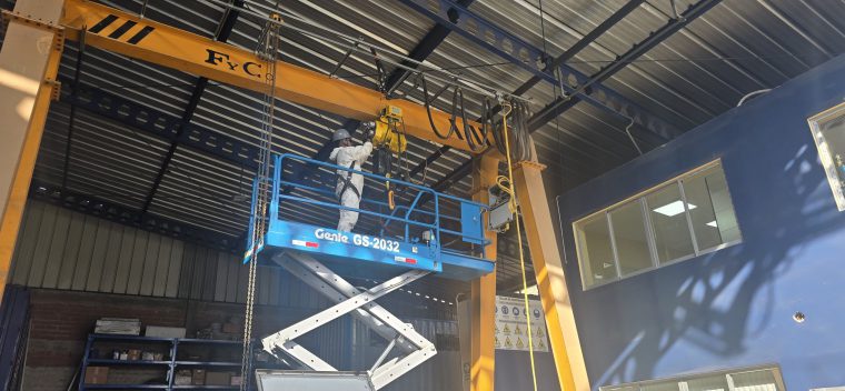 Técnico realizando mantenimiento a un polipasto de grúa puente desde una plataforma elevadora