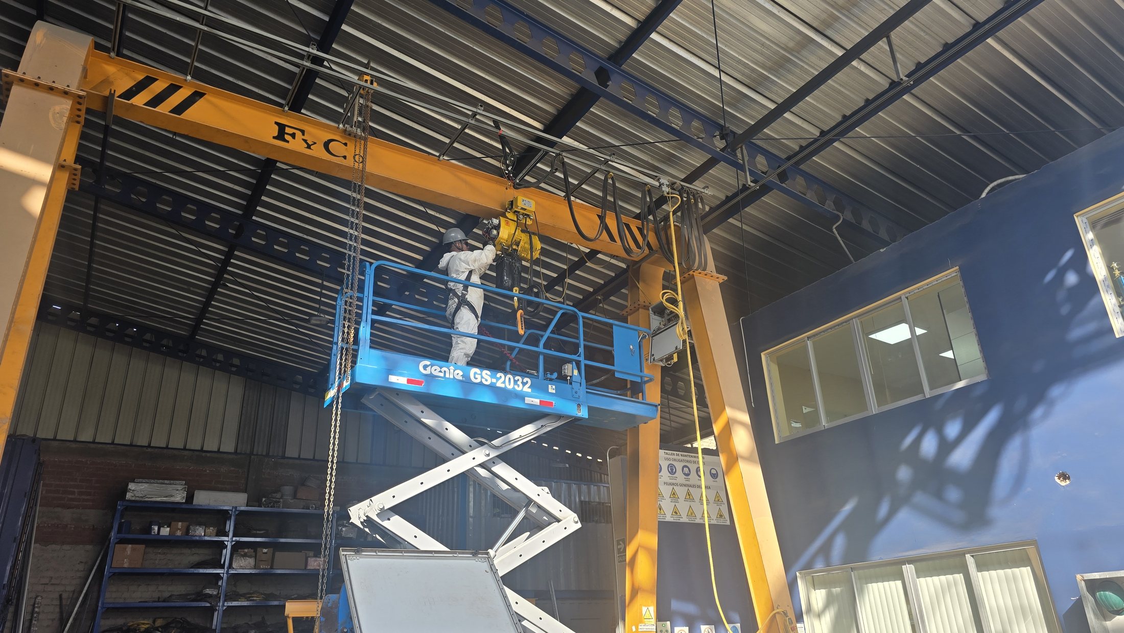 Técnico realizando mantenimiento a un polipasto de grúa puente desde una plataforma elevadora